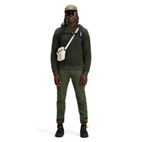 Model wearing Topo Designs Men's Global pullover Sweater recycled washable Italian wool in "Olive" green.