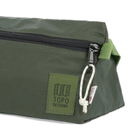 General detail shot of logo patch and zipper pull on Topo Designs TopoLite Dopp Kit ultralight toiletry bag for travel in "olive" green.